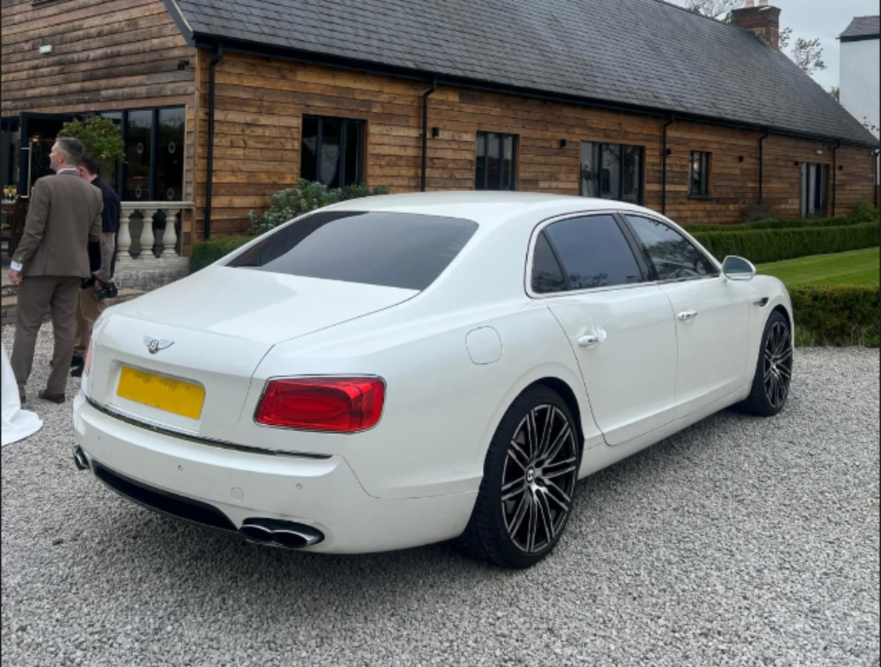 White Bentley Flying Spur luxury wedding car arriving at a countryside wedding venue for Wedding Chauffeur Service Manchester, luxury partner vehicle arranged by MCR EXEC chauffeur transport.