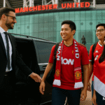 Three Singaporean Manchester United fans wearing red kits step out of a luxury Mercedes V-Class, welcomed by an MCR EXEC chauffeur outside Old Trafford stadium