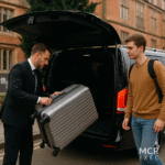 A professional chauffeur assists a Durham University student with luggage outside a black MPV vehicle for a premium airport transfer