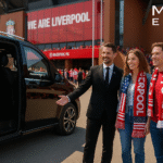 Professional chauffeur welcoming American tourists arriving at Liverpool FC match at Anfield, with luxury black chauffeur van, MCR EXEC logo.