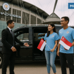 Chauffeur opening luxury car door for Singapore supporters holding Singapore flags at Etihad Stadium - Executive chauffeur to Etihad Stadium for Singaporean football fans - executive chauffeur to Etihad Stadium for Singaporean football fans