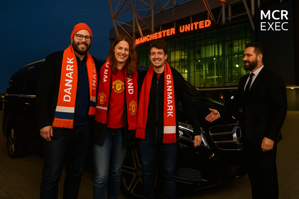 Three Danish Manchester United fans in red scarves and jackets pose outside Old Trafford after arriving in a black Mercedes MPV. A suited chauffeur greets them.