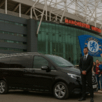 Executive taxi with chauffeur outside Old Trafford for Man Utd vs Chelsea match, Chelsea flag visible