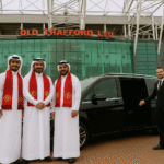 Three Qatari Manchester United fans standing outside Old Trafford with a black MPV and MCR EXEC chauffeur.