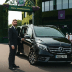 Chauffeur in a black suit stands beside a black Mercedes V-Class outside the iconic Wimbledon Championships entrance, promoting luxury transport with MCR EXEC.