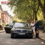 Black Mercedes S-Class with MCR-EXEC plate on Alexandra Road South, Whalley Range, Manchester, chauffeur assisting a passenger in the afternoon light