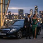 Special occasion chauffeur hire Manchester with a black Mercedes S-Class by MCR-EXEC, showing a professionally dressed chauffeur greeting an elegantly dressed couple outside a modern city venue at dusk, delivering luxury chauffeur transport for a formal evening event.