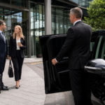 Corporate Chauffeur Account Manchester image showing professional business travellers being collected by a chauffeur outside a modern city office, with a black executive Mercedes-style vehicle for premium corporate travel.
