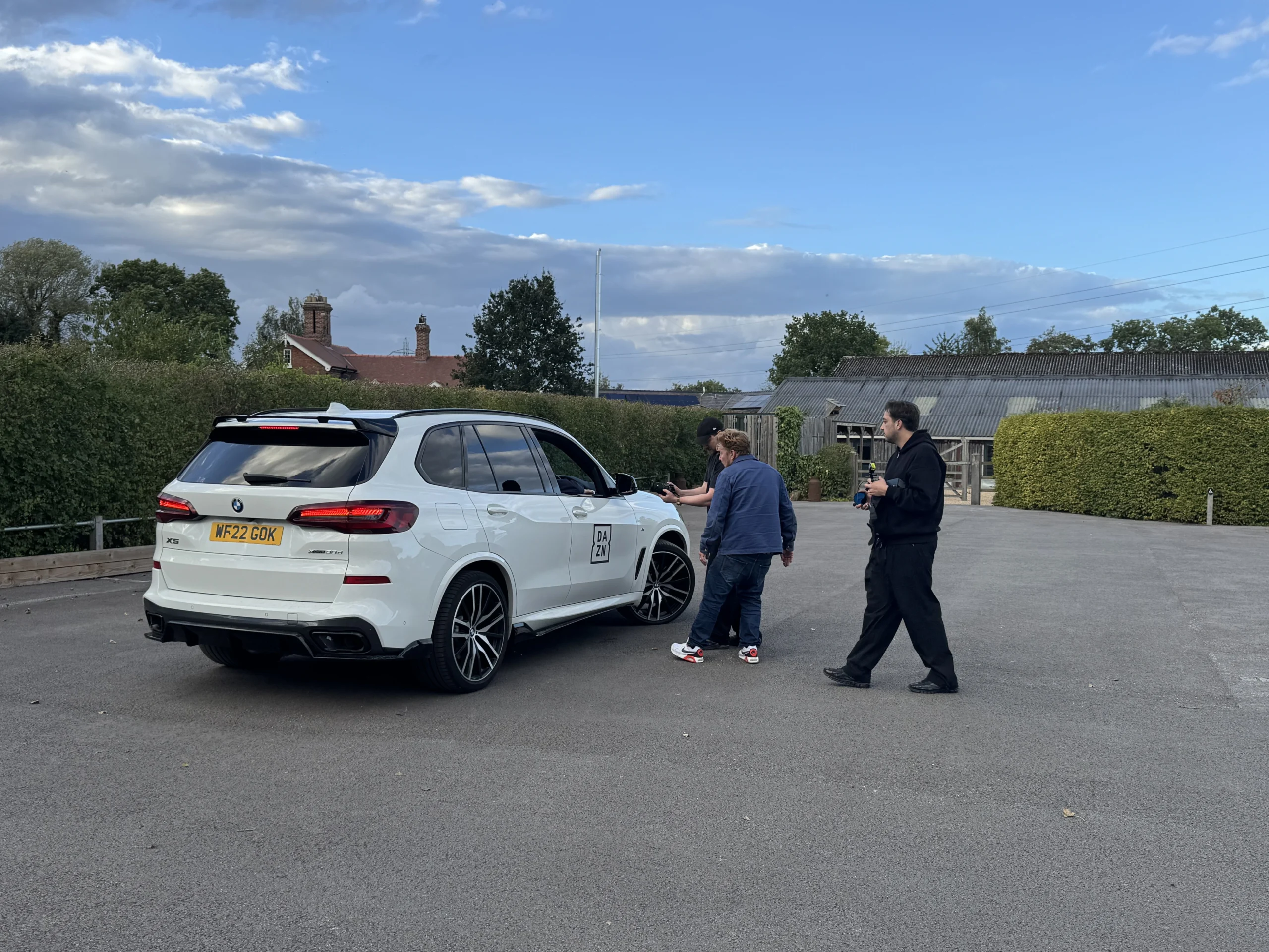 People beside a white production vehicle at a rural filming location in Mobberley