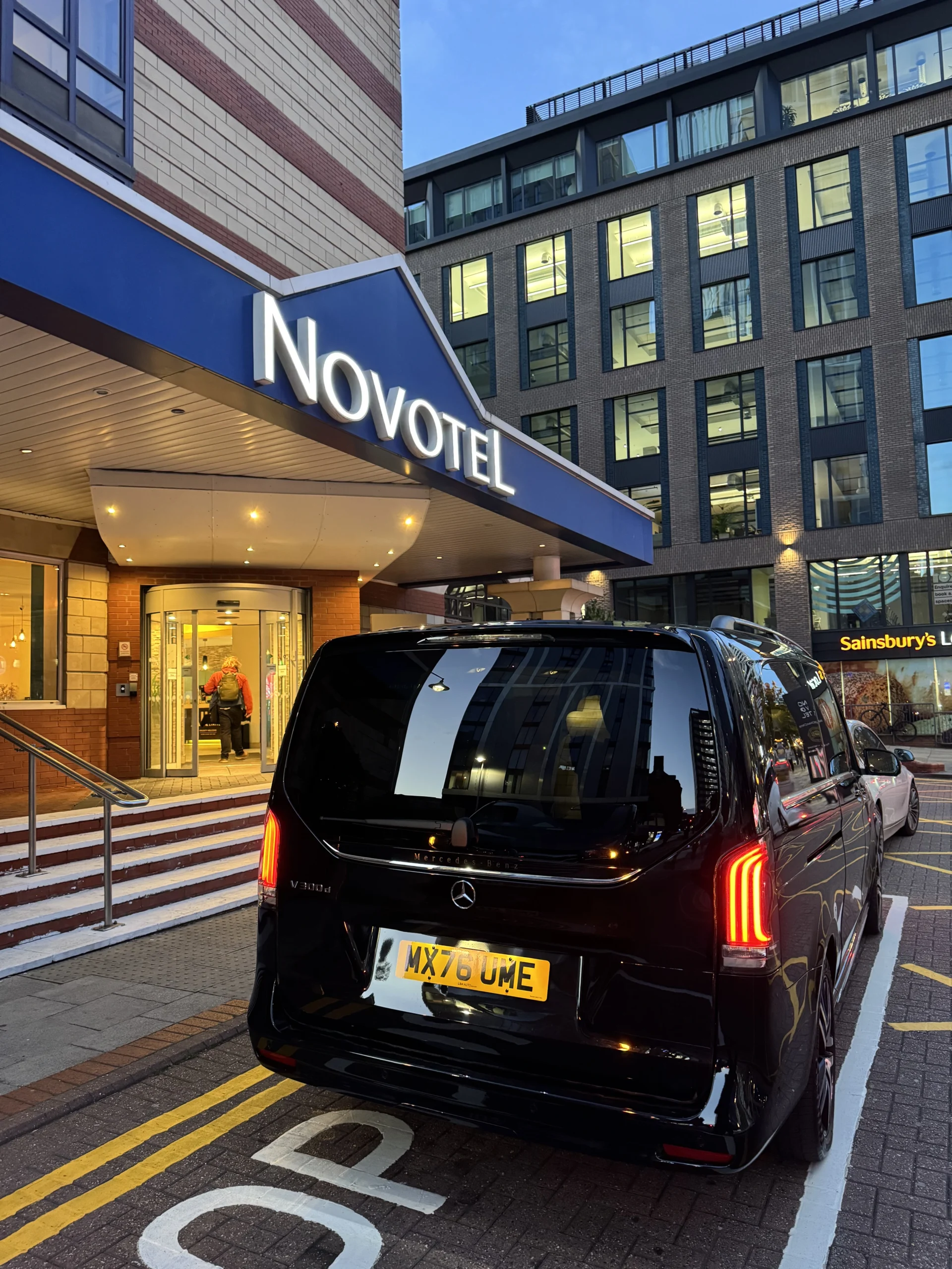 Black MCR EXEC Mercedes V-Class outside the Novotel hotel in Birmingham in the evening