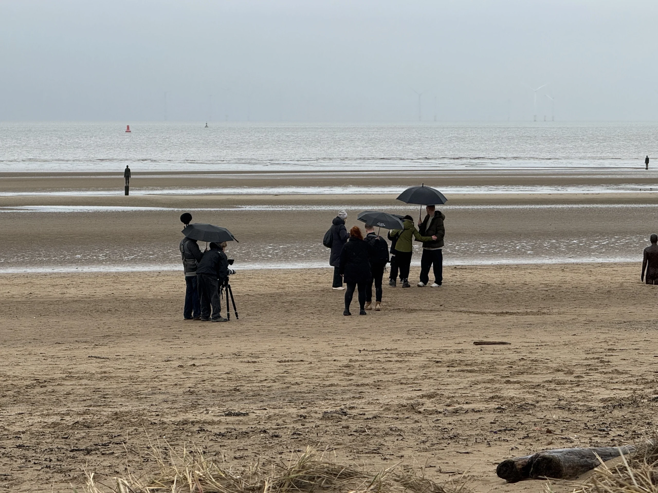 Tripadvisor production team filming on Crosby Beach with a camera, sound equipment and umbrellas